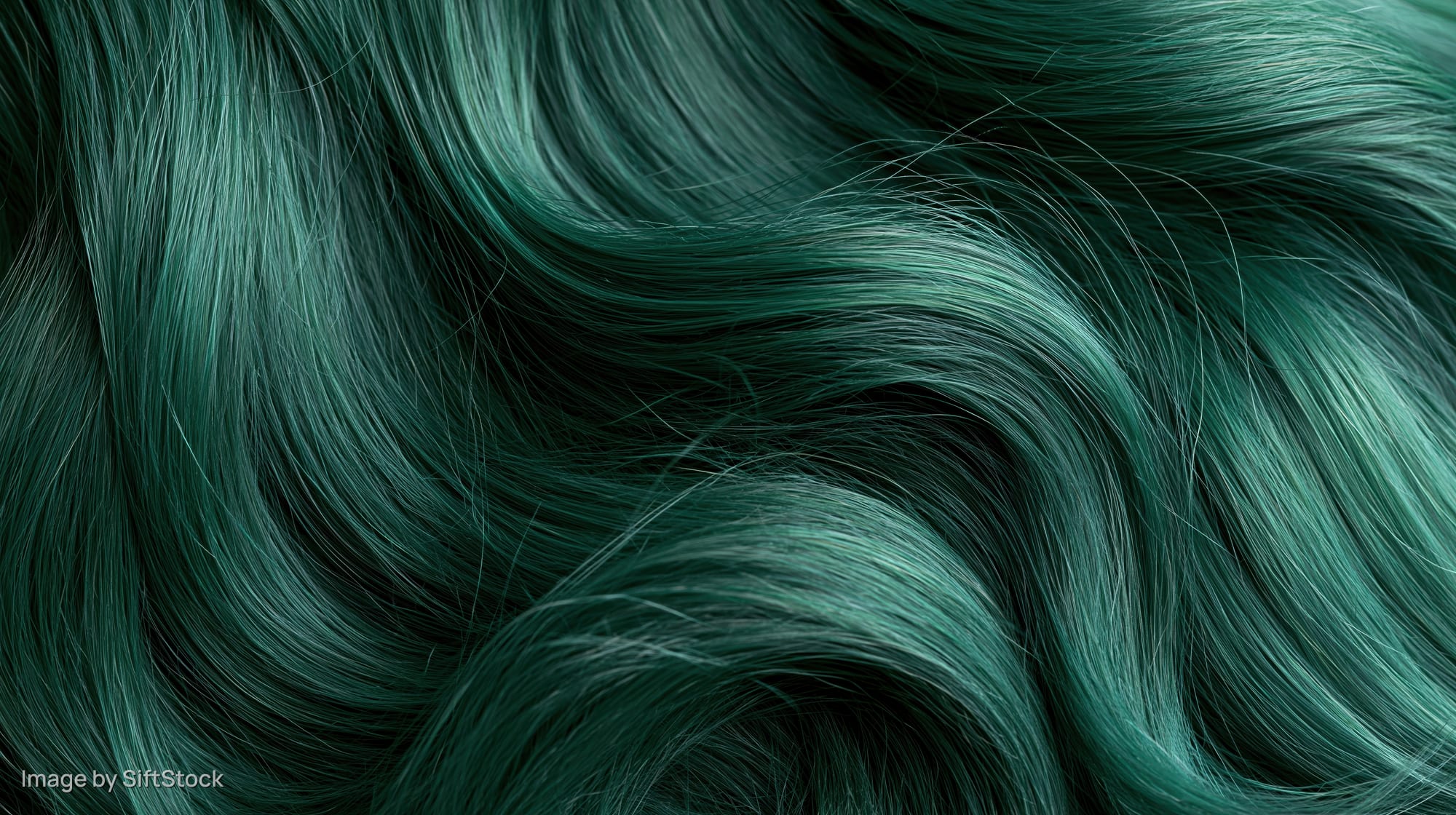 Close-up of wavy emerald green dyed hair with glossy texture