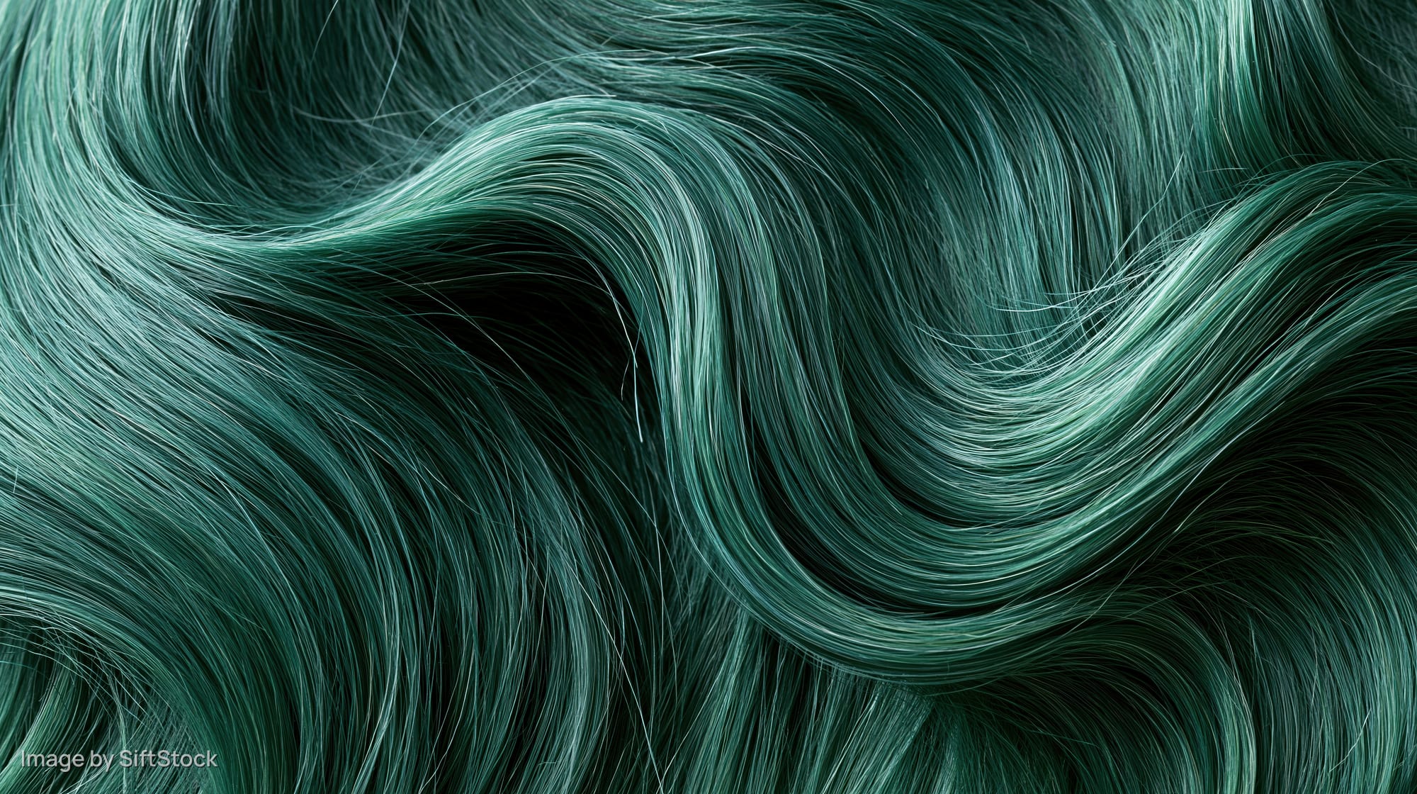 Close-up of emerald green dyed hair with glossy waves and smooth texture