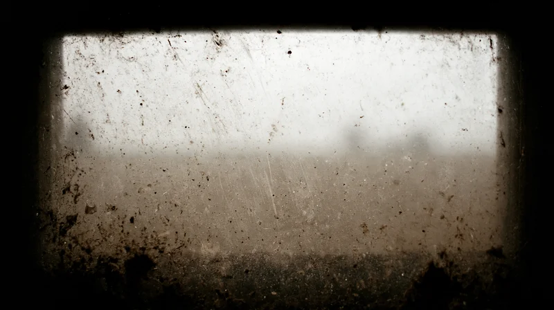 Dirty window pane covered in grime and scratches viewed from inside a dark space