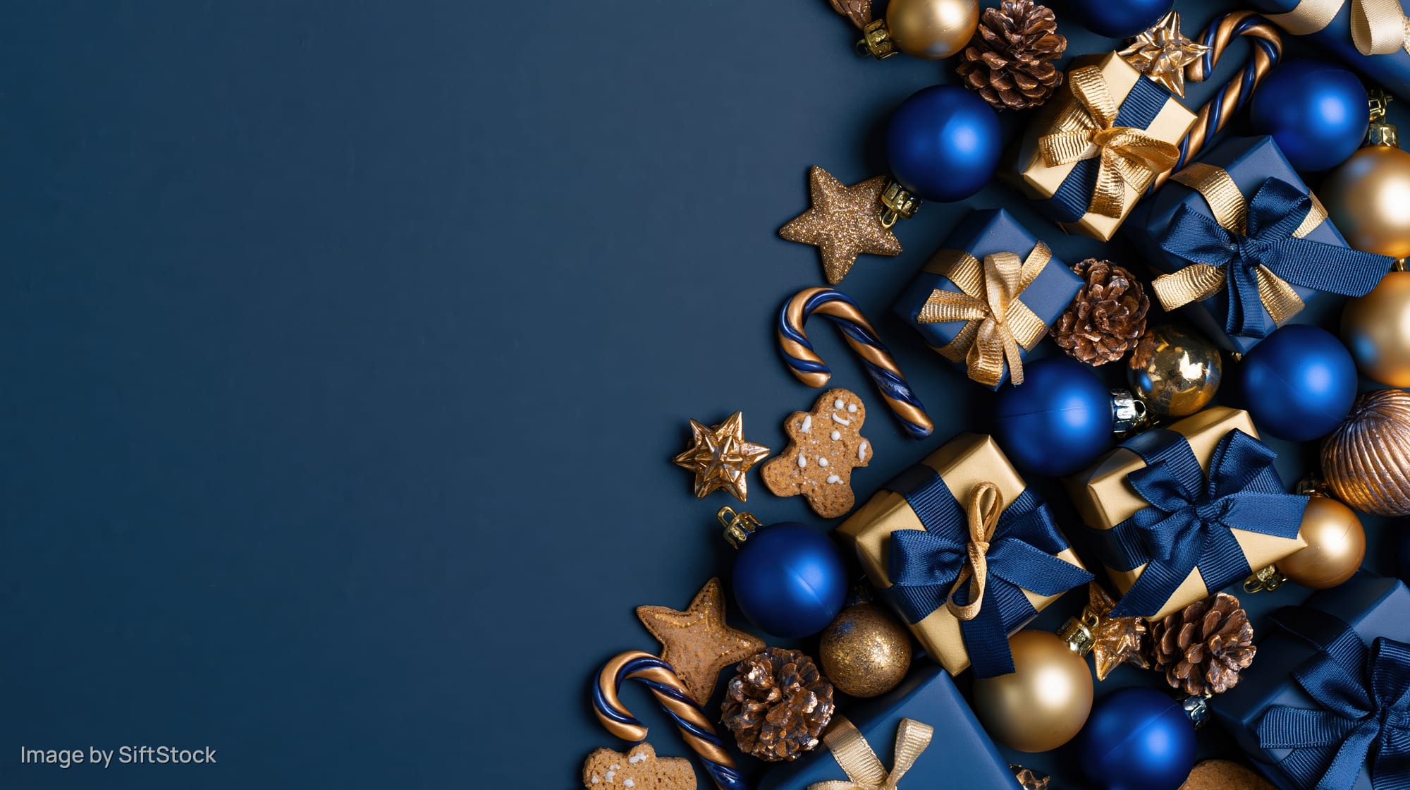 Christmas decorations and gifts arranged in corner on dark blue surface with copyspace