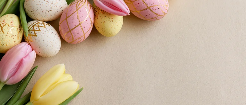 Easter eggs and tulips arranged in a flat lay on a beige surface with copyspace