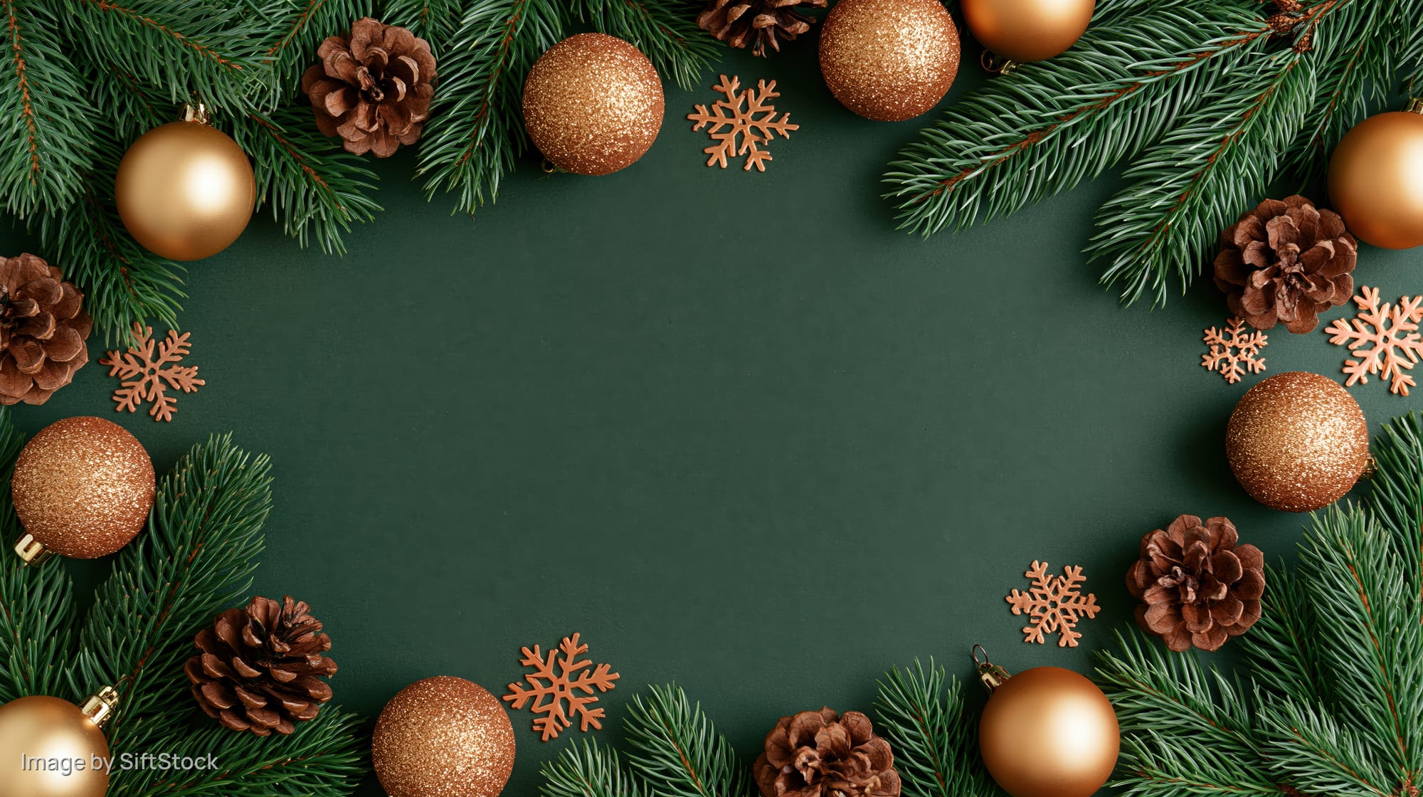 Spruce branches and gold ornaments arranged in a frame on dark green background with copyspace