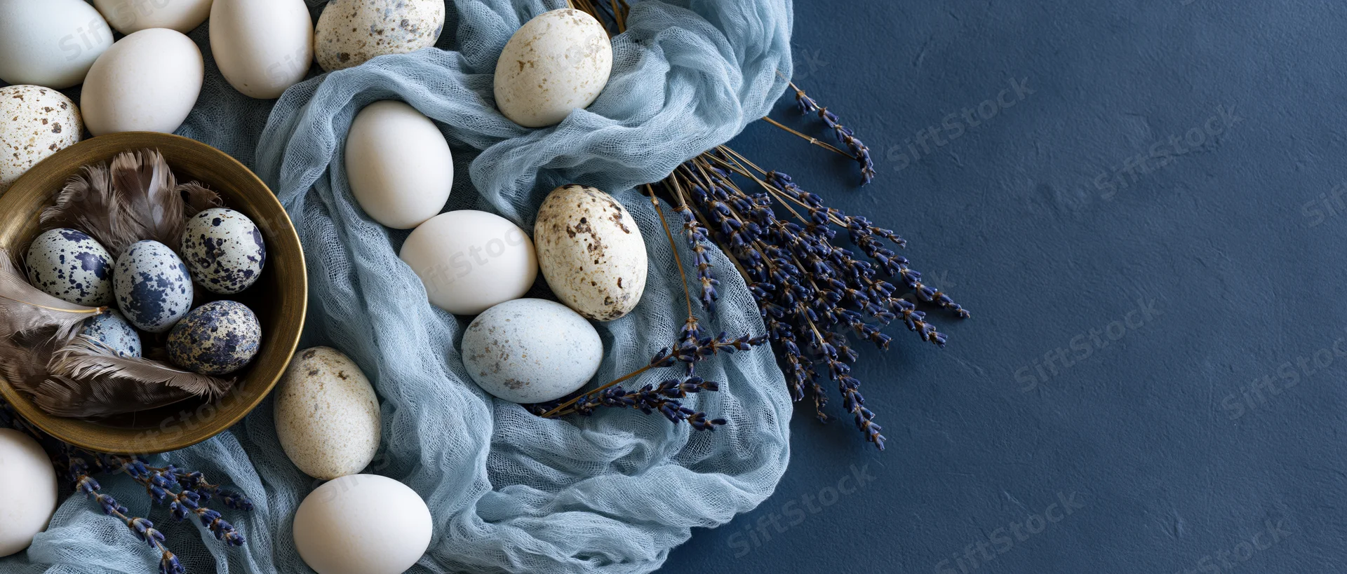 Easter eggs and lavender arranged on draped fabric with copyspace