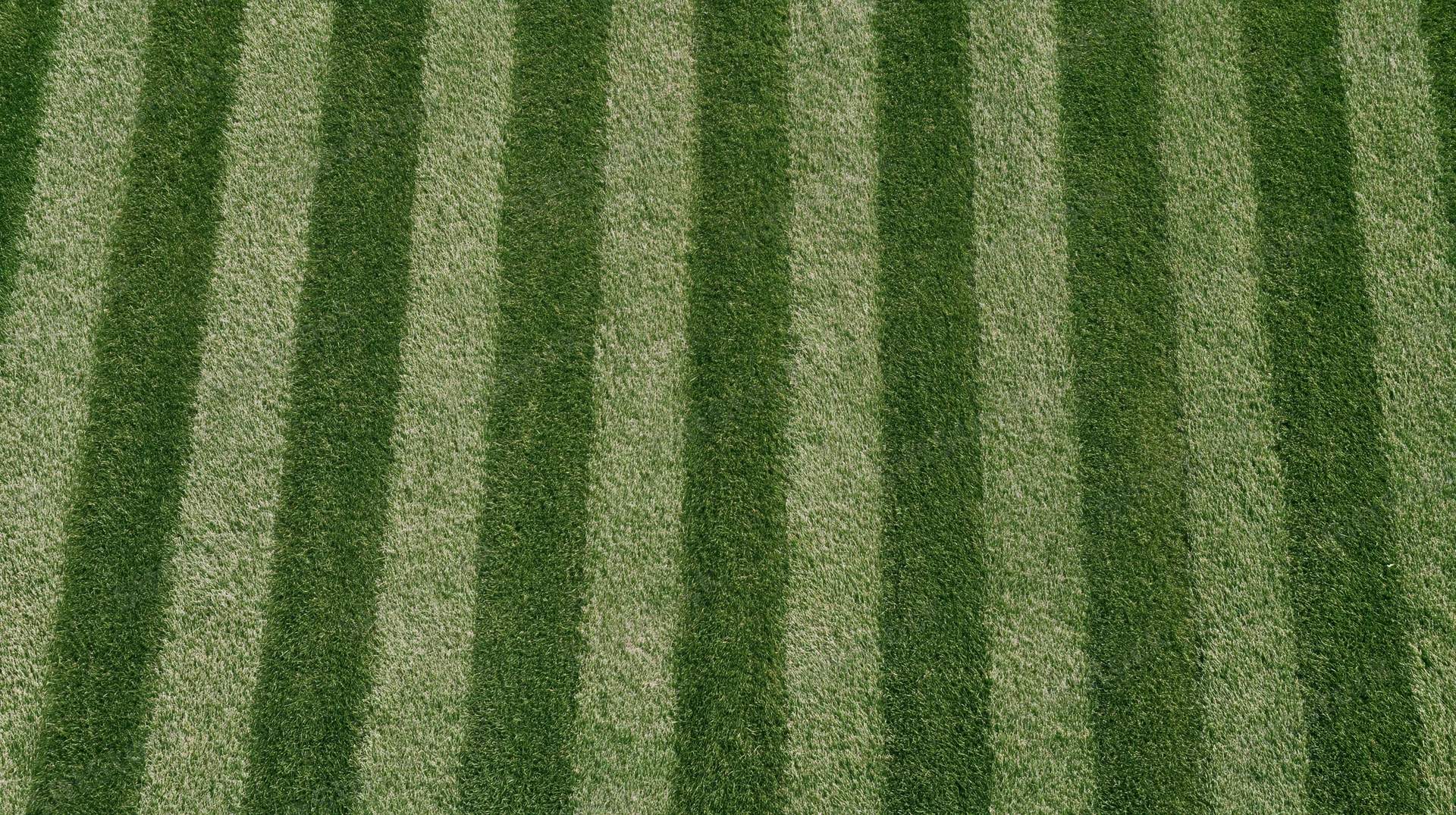 Overhead view of freshly mowed grass sports field with alternating green stripes