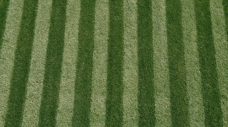 Overhead view of freshly mowed grass sports field with alternating green stripes