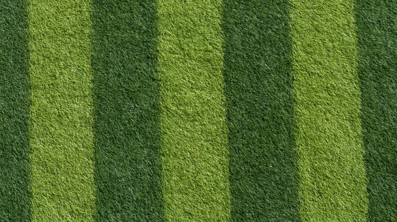 Freshly mowed grass with alternating green stripes viewed from above on a sports field