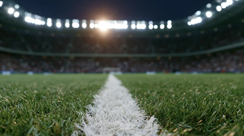 Ground-level view of a football pitch center line under stadium lights at night