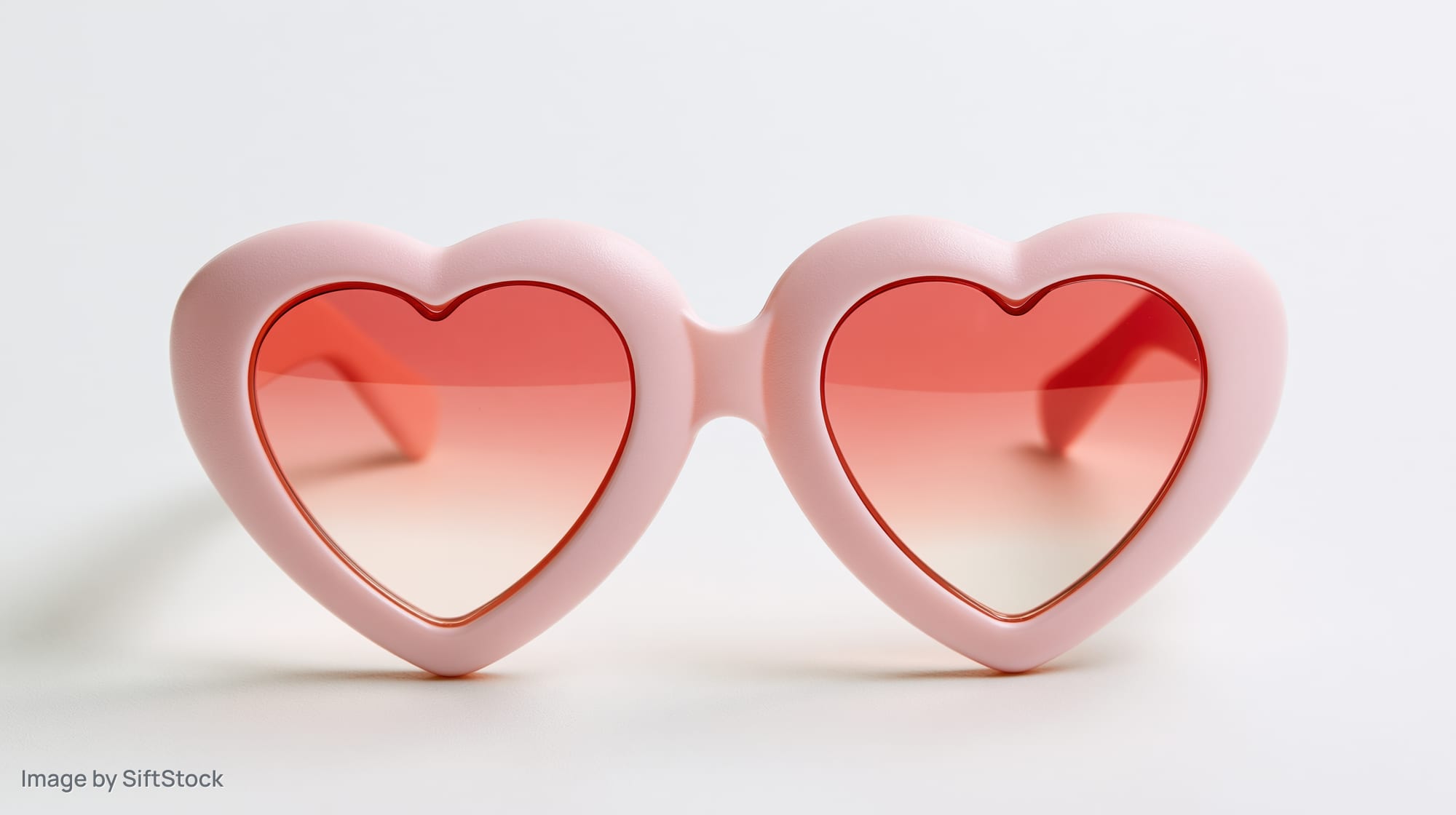 Heart-shaped pink novelty sunglasses on a white surface