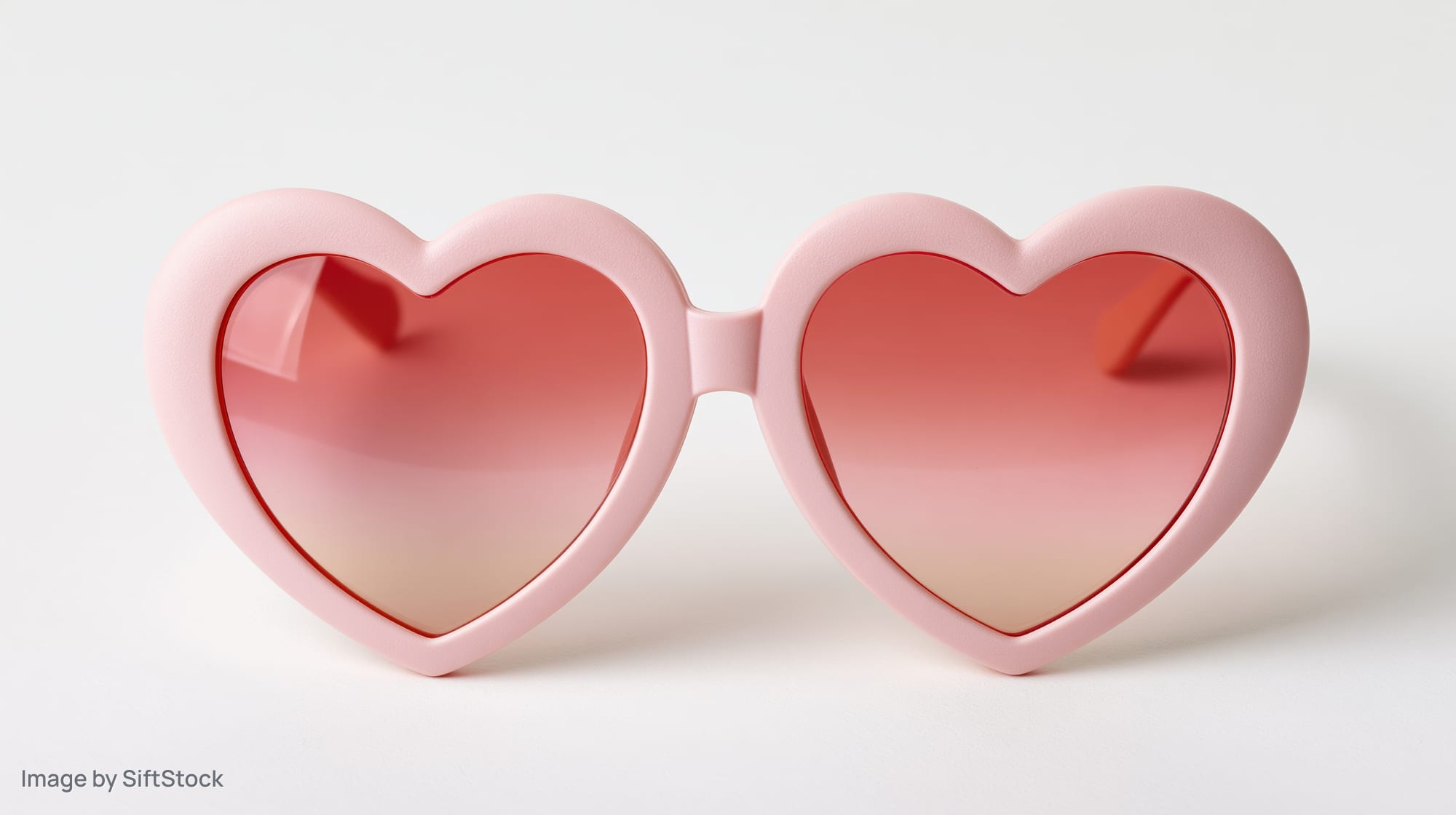 Heart-shaped novelty sunglasses with pink plastic frames on white background