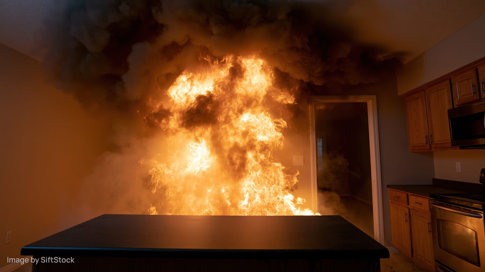 Intense fire burning in a residential kitchen interior with thick smoke and flames engulfing the space
