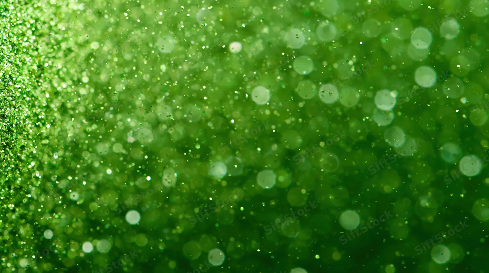 Macro closeup of suspended green glitter particles floating in soft focus with bokeh highlights
