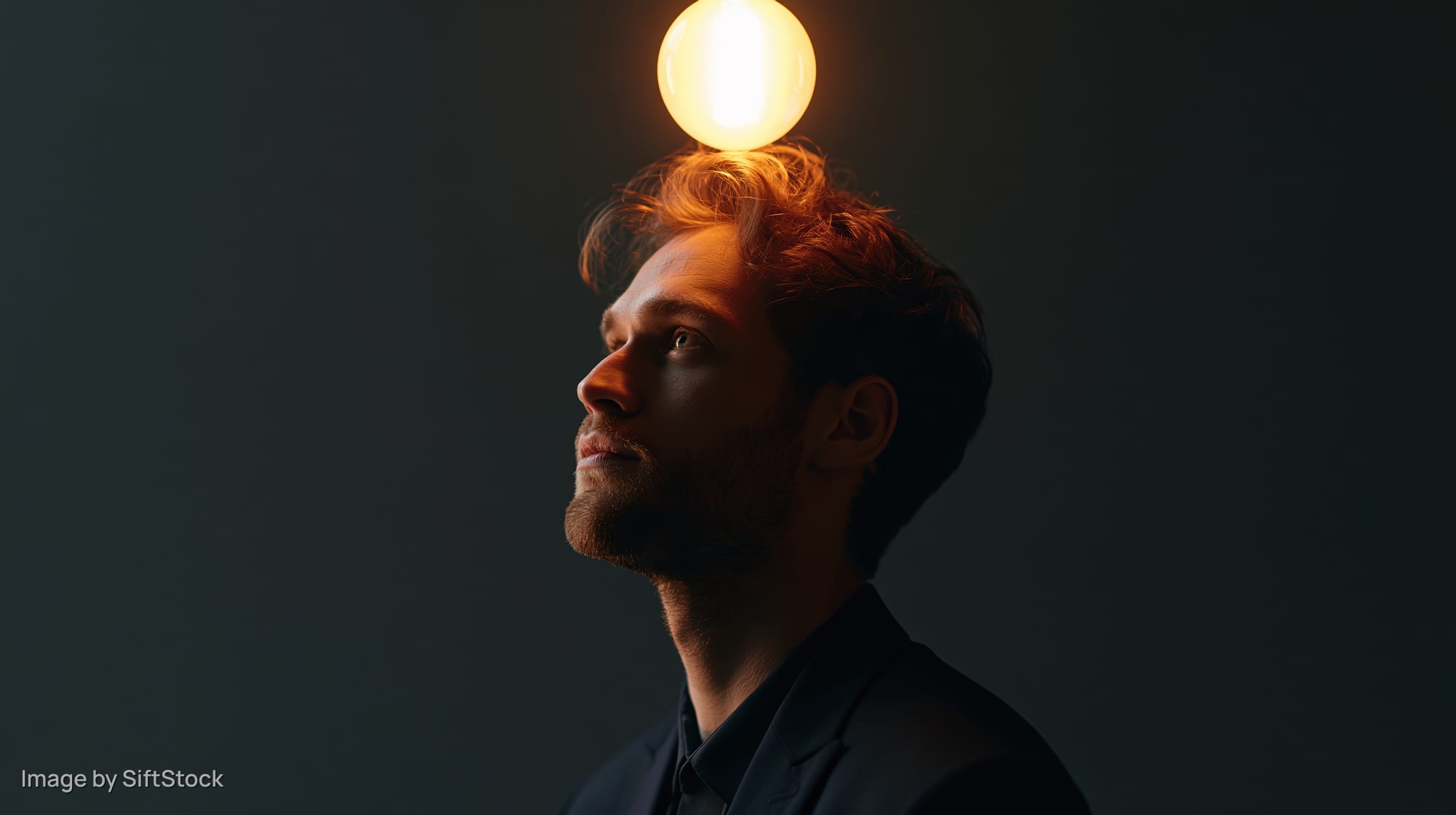 Man in profile with lightbulb above his head against dark background