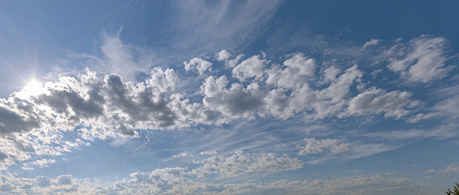 Open sky with scattered cumulus and wispy alto clouds during daytime