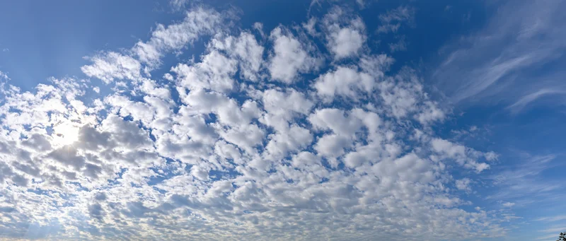 Open sky with scattered cumulus and wispy alto clouds during daytime