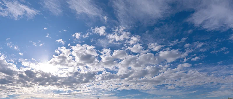 Open sky with scattered cumulus and wispy alto clouds during daytime