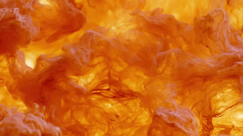 Orange and amber ink swirling in water in extreme closeup