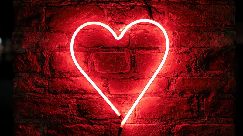 Red neon heart sign glowing on a dark brick wall