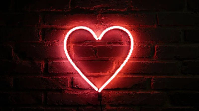 Red neon heart sign glowing on dark brick wall