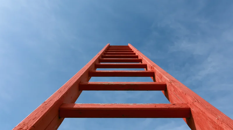Red wooden ladder rising vertically into open blue sky viewed from below