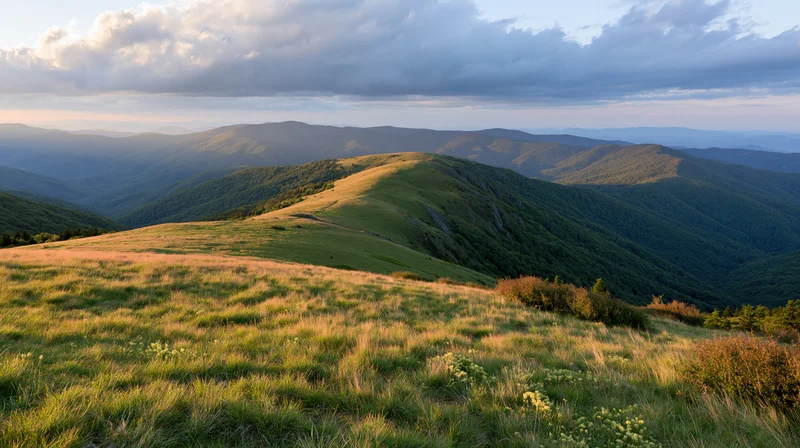 Rolling green mountain ridges under a dramatic partly cloudy sky at sunset