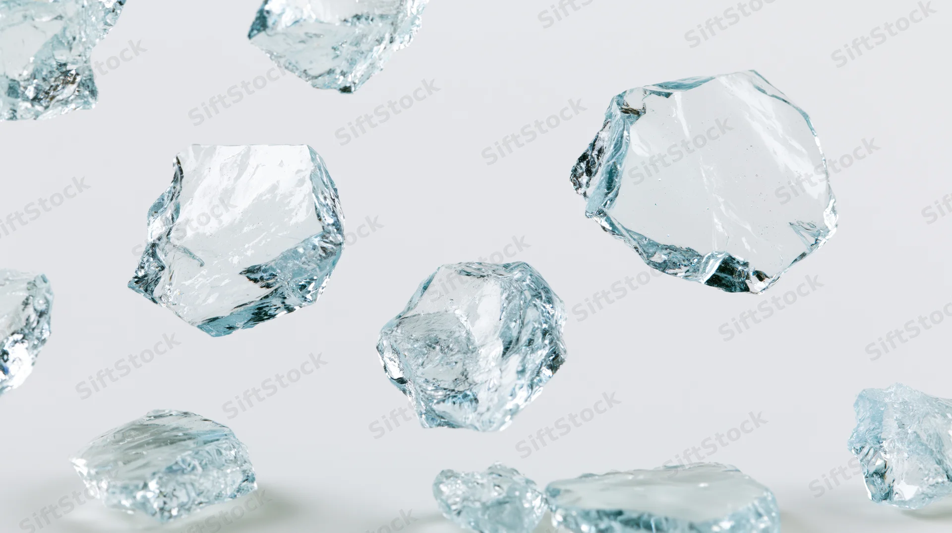 Broken glass shards floating in midair against a white background