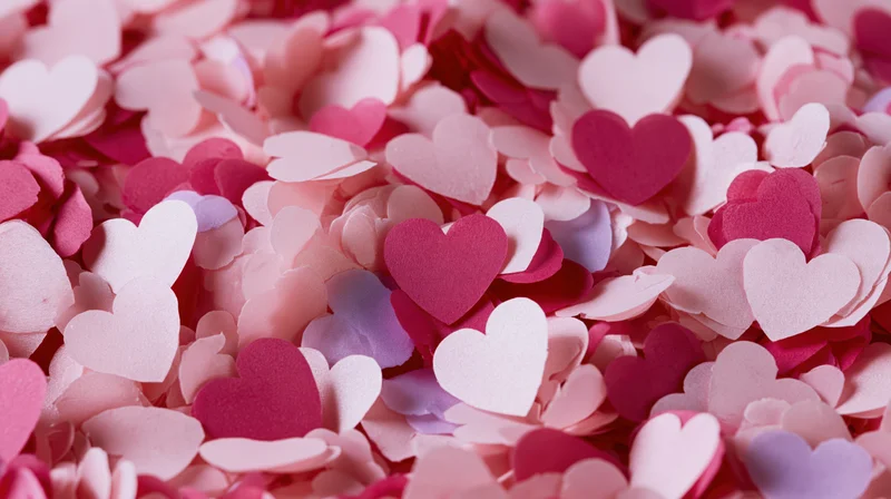 Scattered paper hearts in pink and white tones covering a flat surface