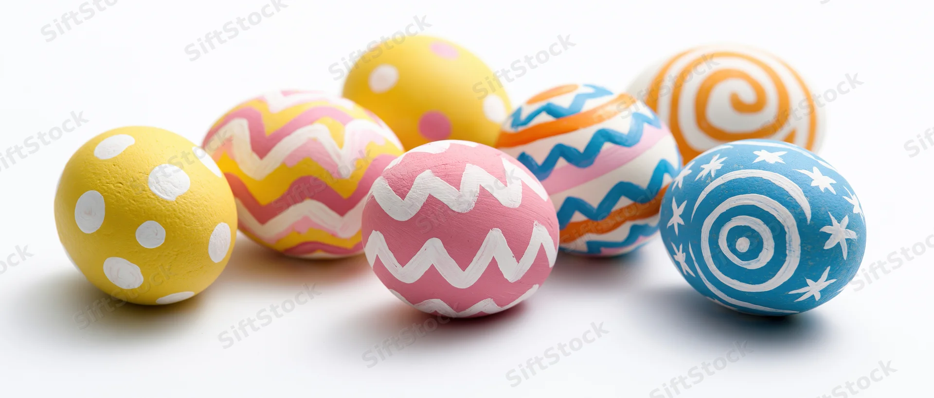 Seven hand-painted easter eggs with colorful patterns arranged loosely on white background