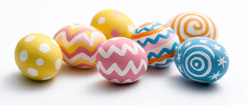 Seven hand-painted easter eggs with colorful patterns arranged loosely on white background