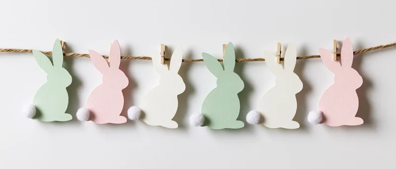 Paper easter bunny cutouts clipped to a string garland on a white wall