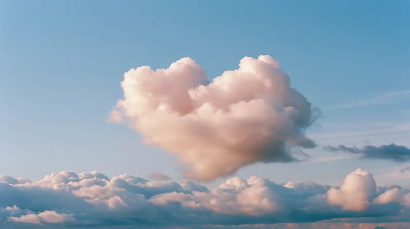 Heart-shaped cumulus cloud floating in a soft blue sky with pink and white tones at twilight