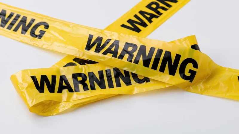 Yellow plastic warning tapes crossed over each other on white background