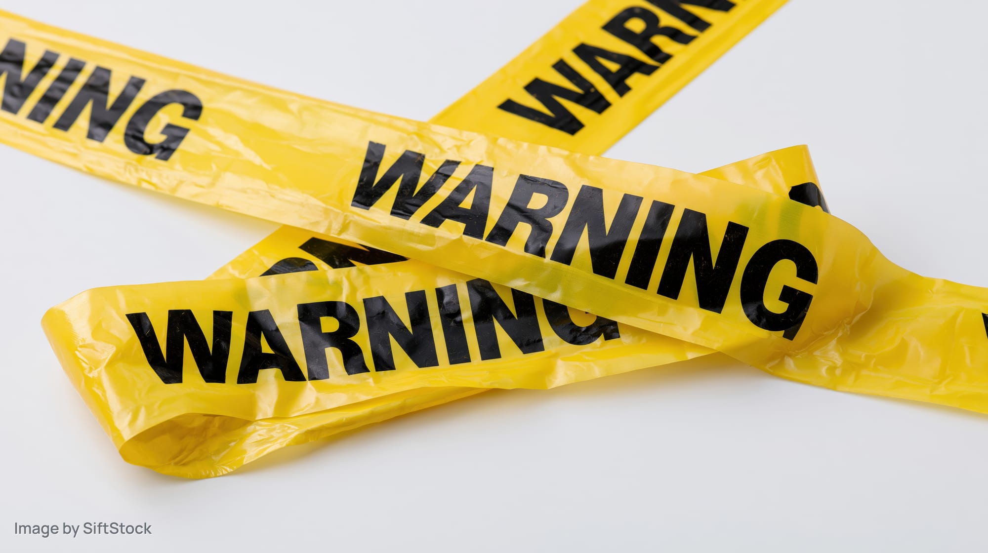 Yellow plastic warning tapes crossed over each other on white background