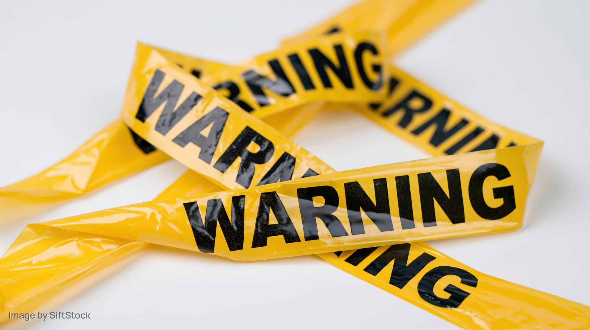 Yellow plastic warning tapes crossed over each other on white background