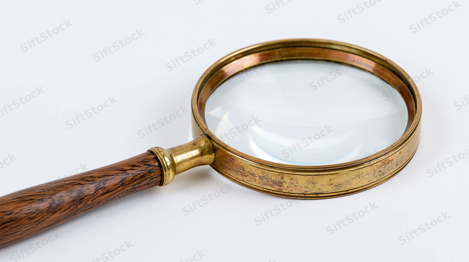 Vintage brass magnifying glass with dark wood grain handle on white background
