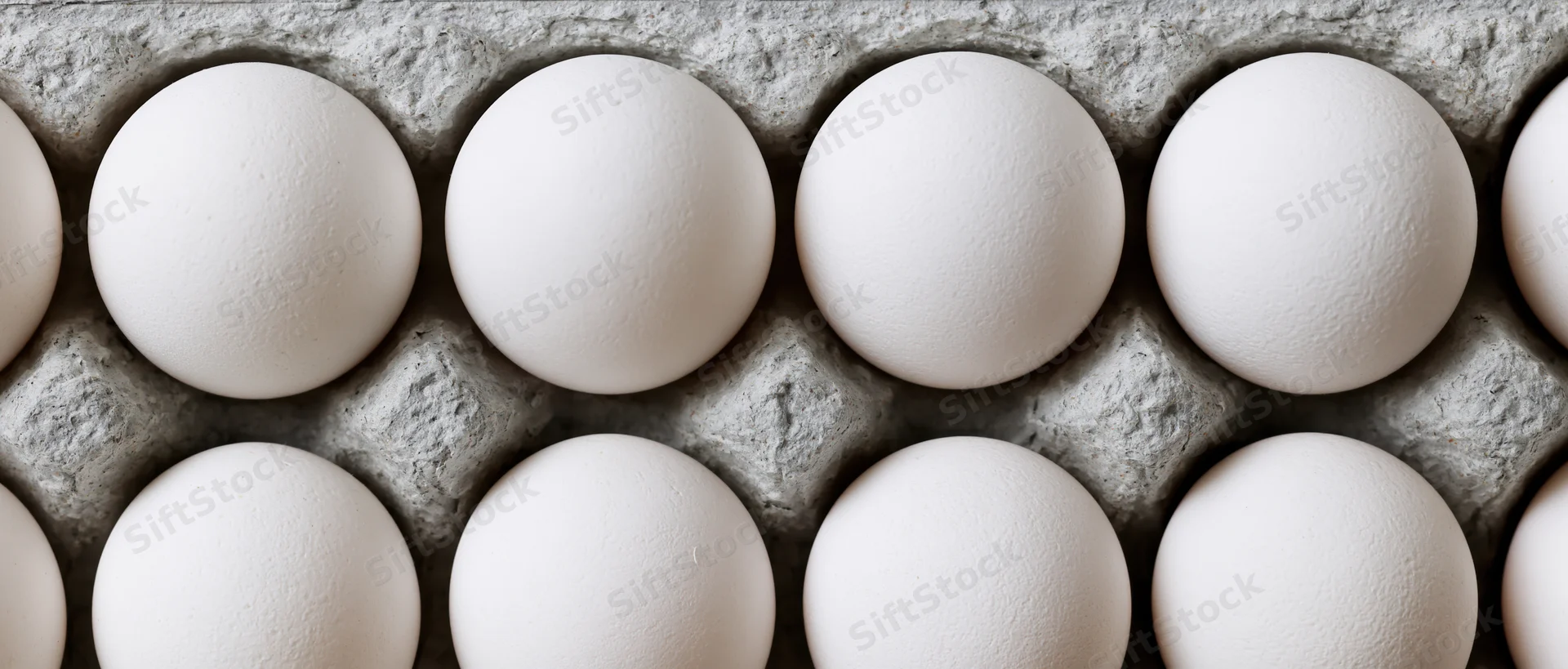 White chicken eggs arranged in a grey cardboard carton