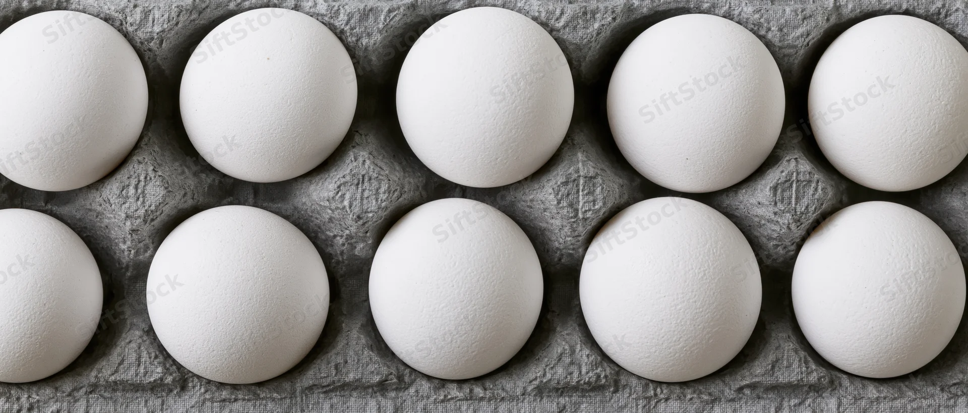 White chicken eggs arranged in a grey cardboard carton