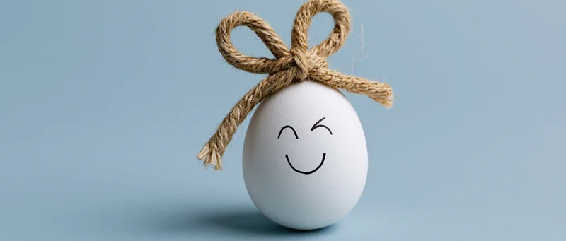 White egg decorated with jute twine bow and smiling face for easter
