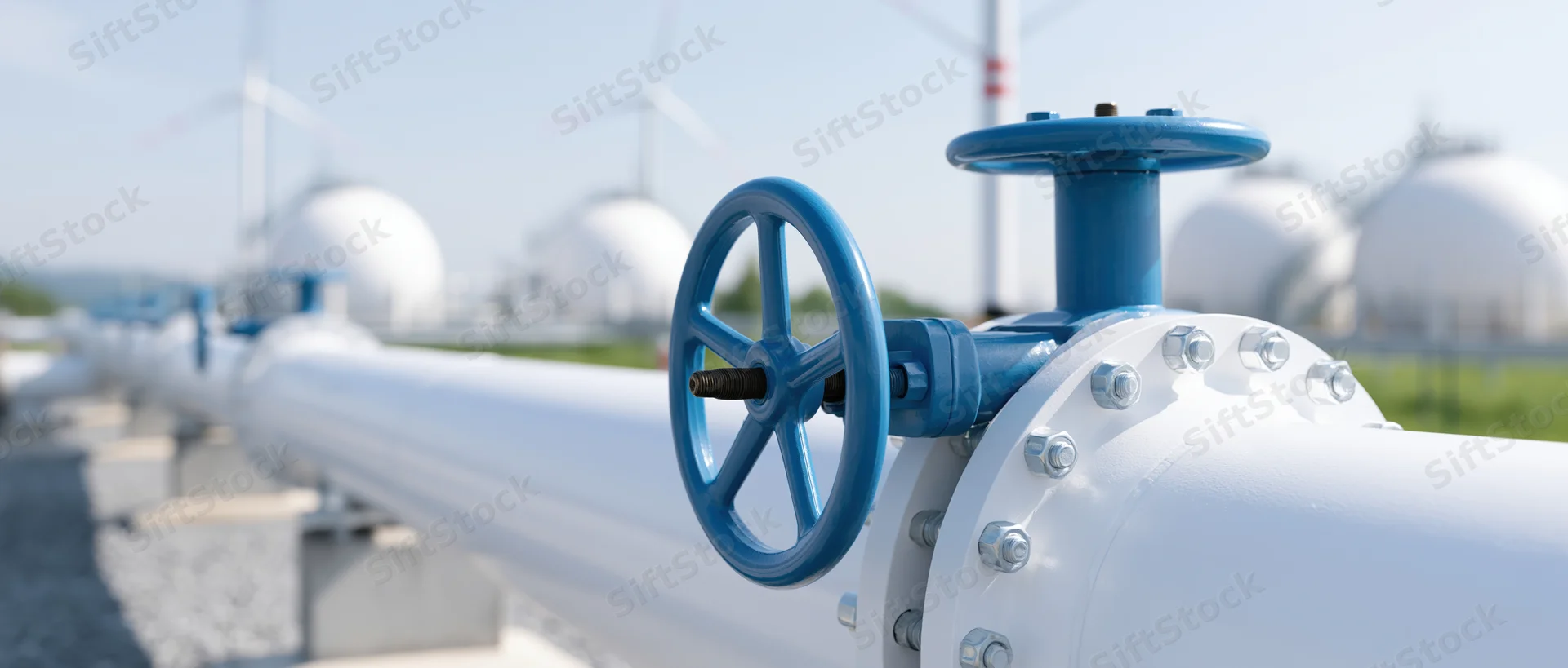 White industrial hydrogen pipeline with blue valve wheels running through a renewable energy facility