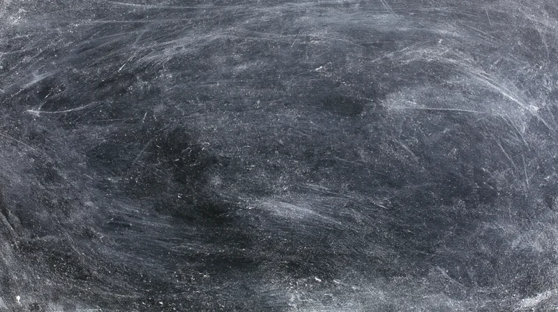 Worn blackboard surface with chalk residue and smudges, showing texture and use marks
