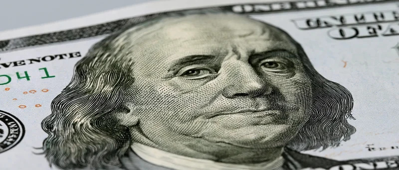 Closeup of a hundred dollar bill showing benjamin franklin's portrait and security details
