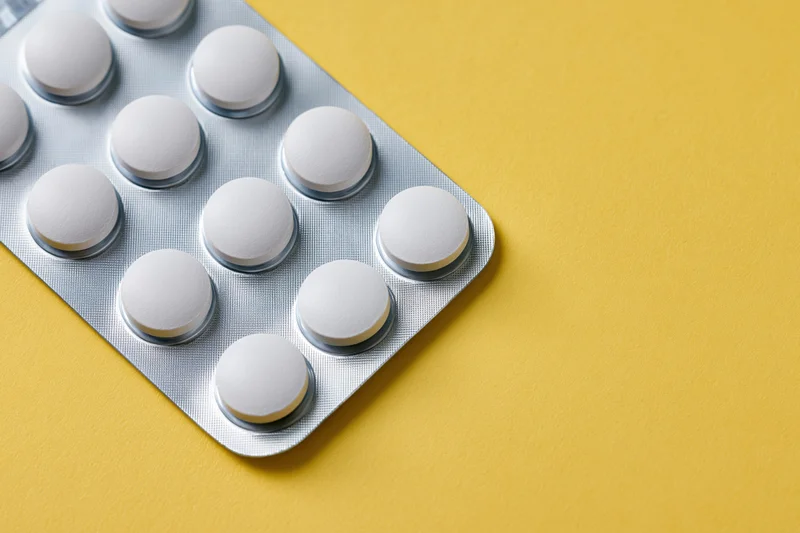 Blister pack of white tablets on yellow surface with copyspace