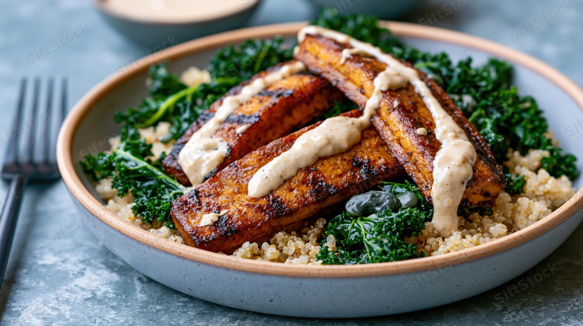 Grilled tofu slabs with sautéed kale and quinoa in a ceramic bowl