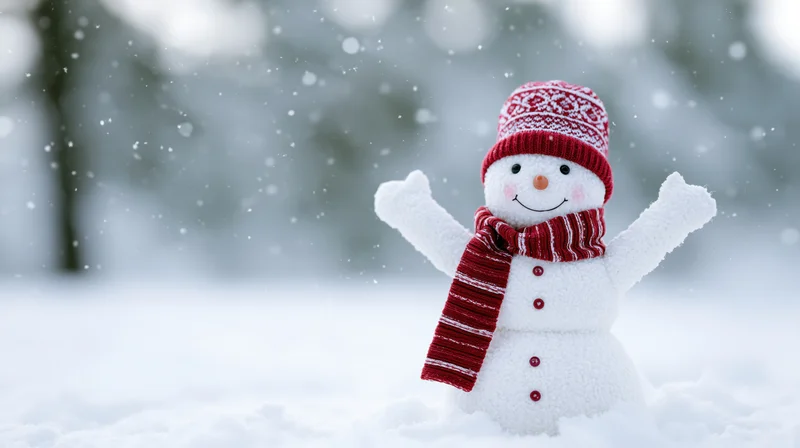 Cheerful snowman toy figurine with red hat and scarf standing in fresh snow with arms raised