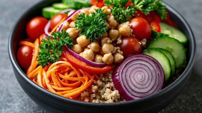 Dark ceramic bowl filled with quinoa salad topped with chickpeas, vegetables and parsley