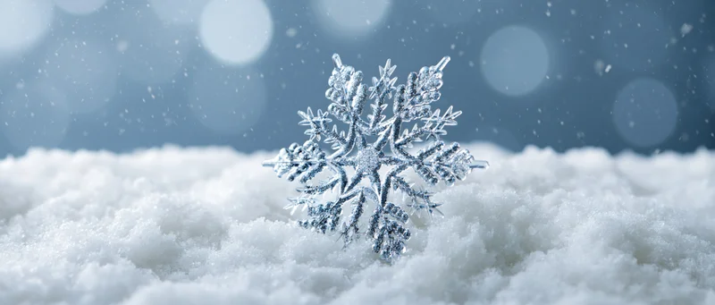 Crystal snowflake ornament resting on soft snow with bokeh background