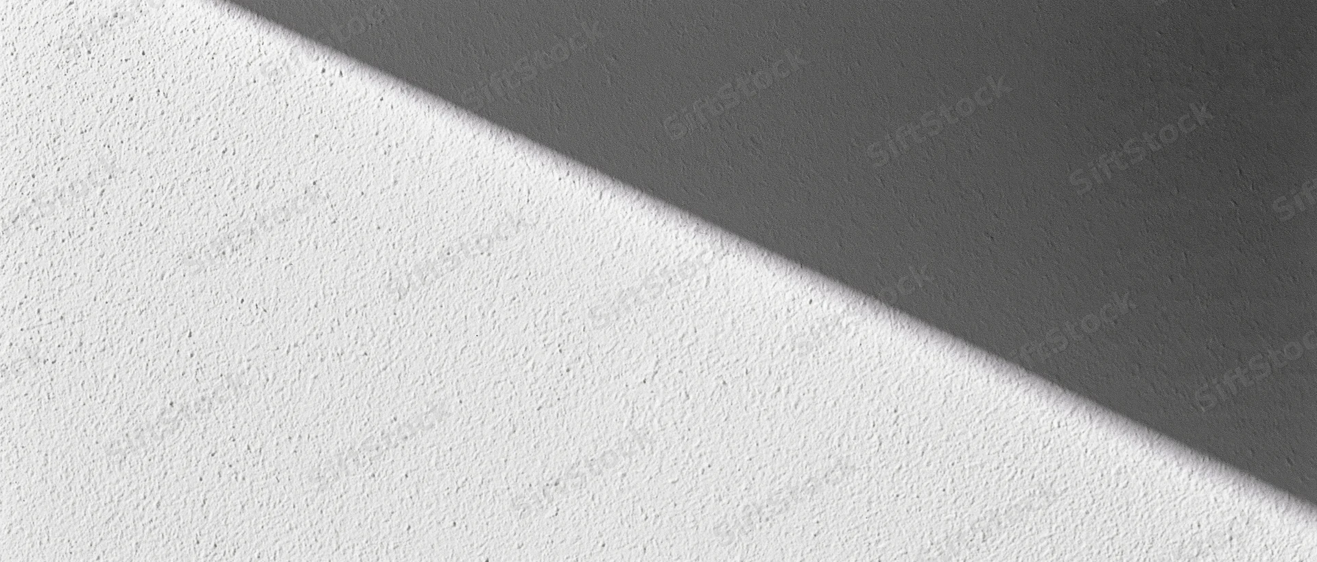 Diagonal shadow across a matte plaster wall in an interior space