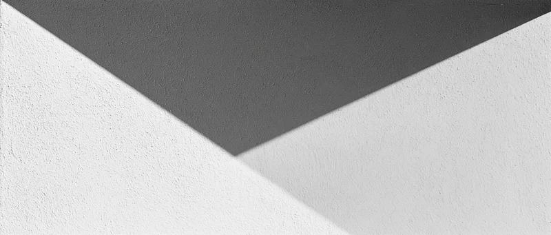 Diagonal shadow across a plain matte plaster wall in an interior space