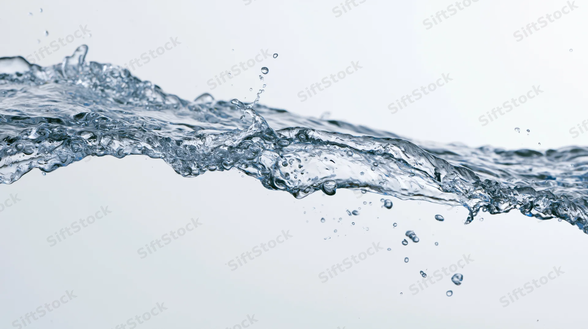 Dynamic water splash frozen mid-motion forming an elongated wave against a white background