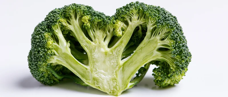 Broccoli cut in half arranged into a heart shape on white background