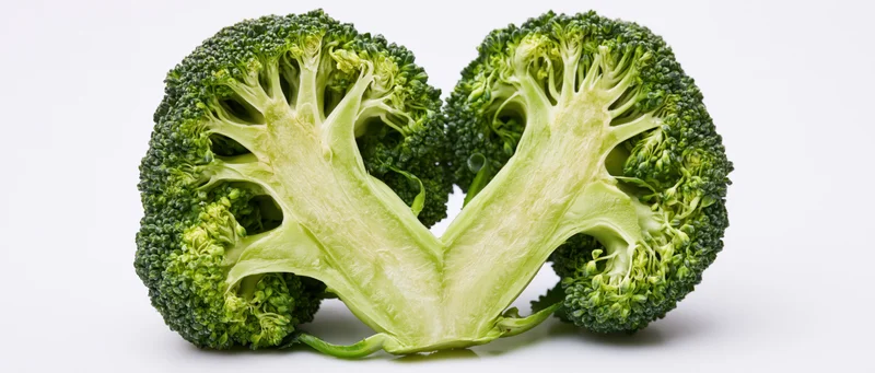 Broccoli halves arranged in heart shape on white background